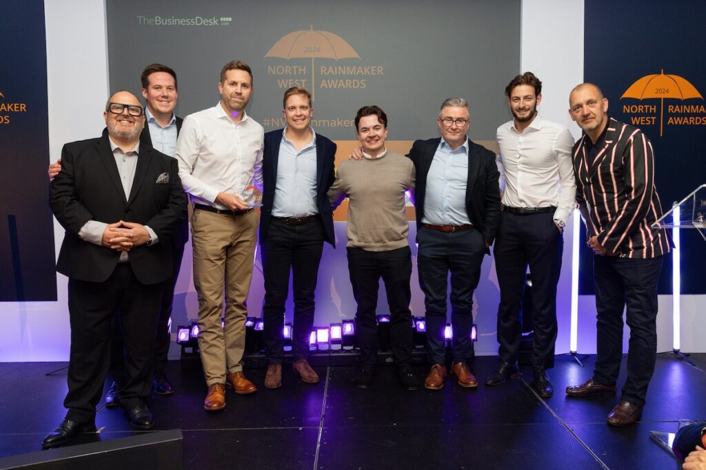 A group shot of a man looking happy and accomplished accepting an award