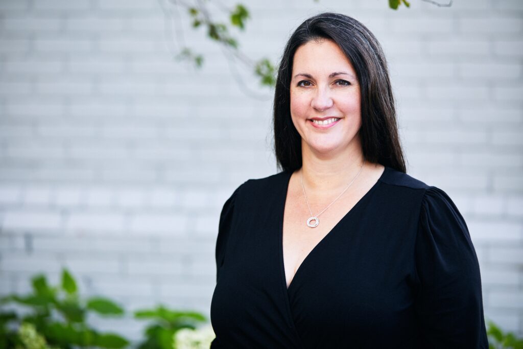 An image of a smiling woman in front of an office building
