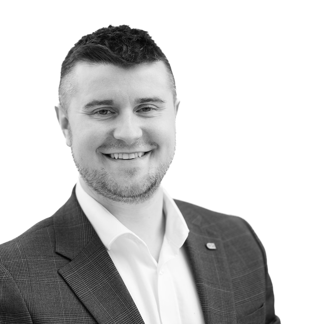 A black and white headshot image of a smiling man against a white backdrop