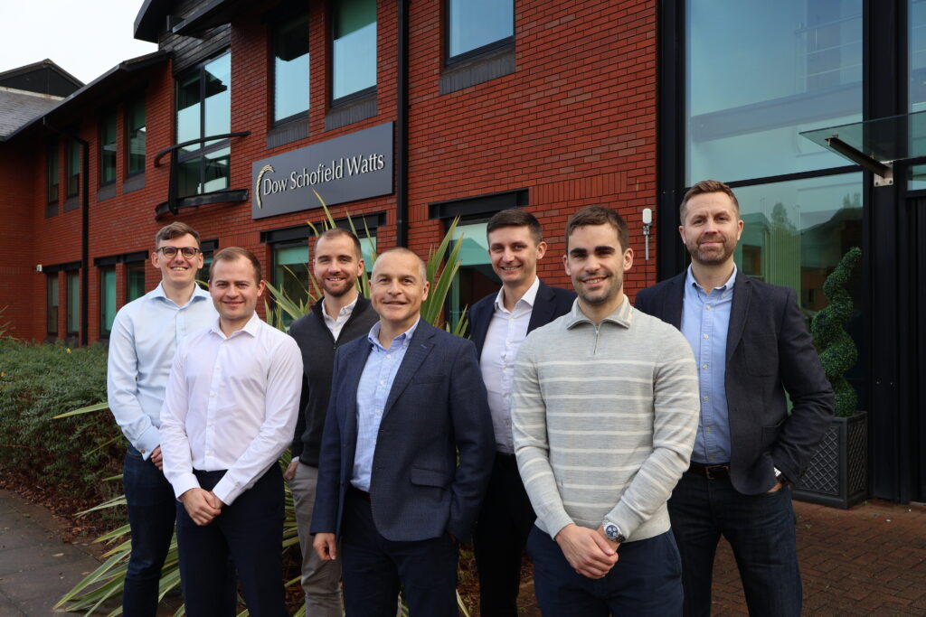 A group photo of DSW's Corporate Finance team standing in front of the office building.