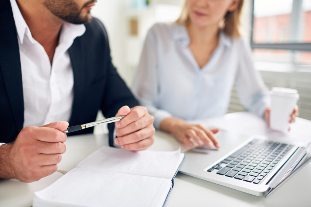 Midsection of business people working with coffee cups on desk at office