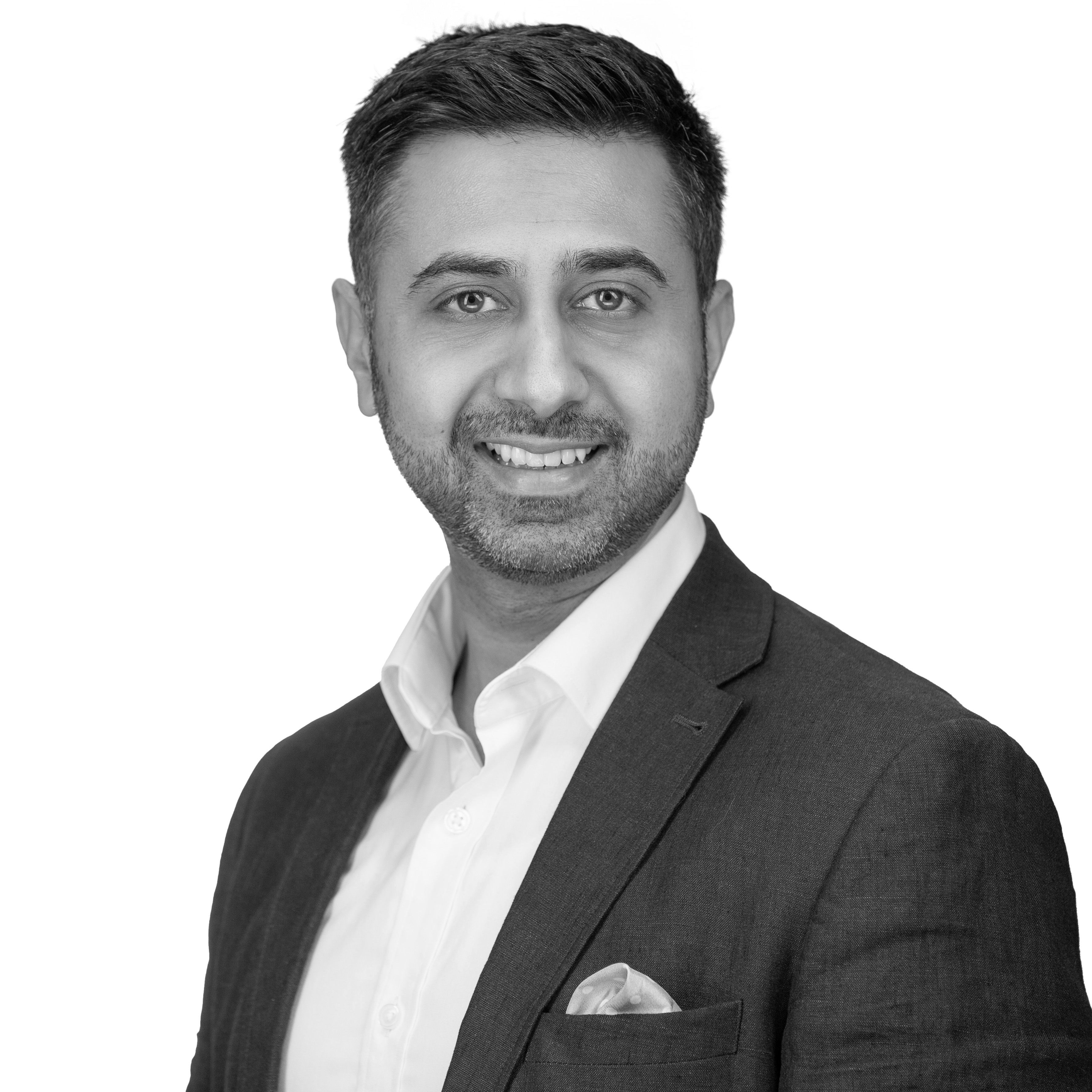 A black and white headshot image of a smiling man against a white backdrop