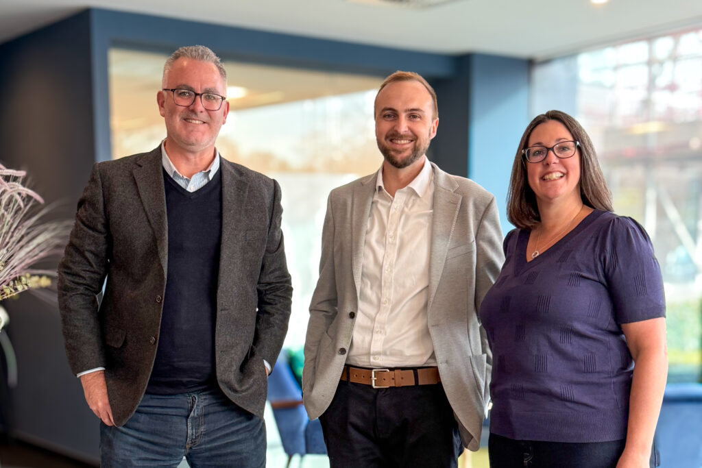 A group photo of two men and a woman smiling in an office.