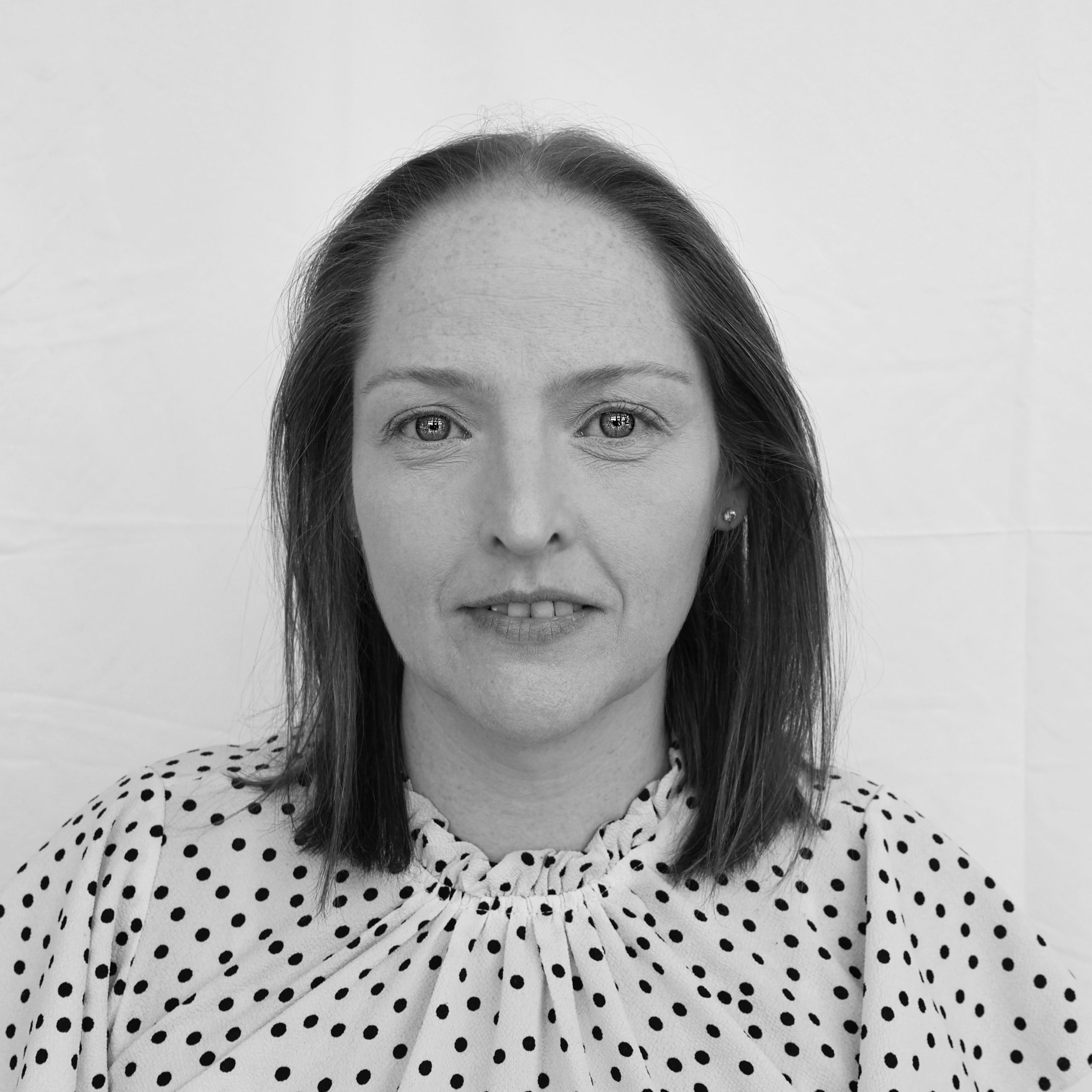 A black and white headshot image of a smiling woman against a white backdrop