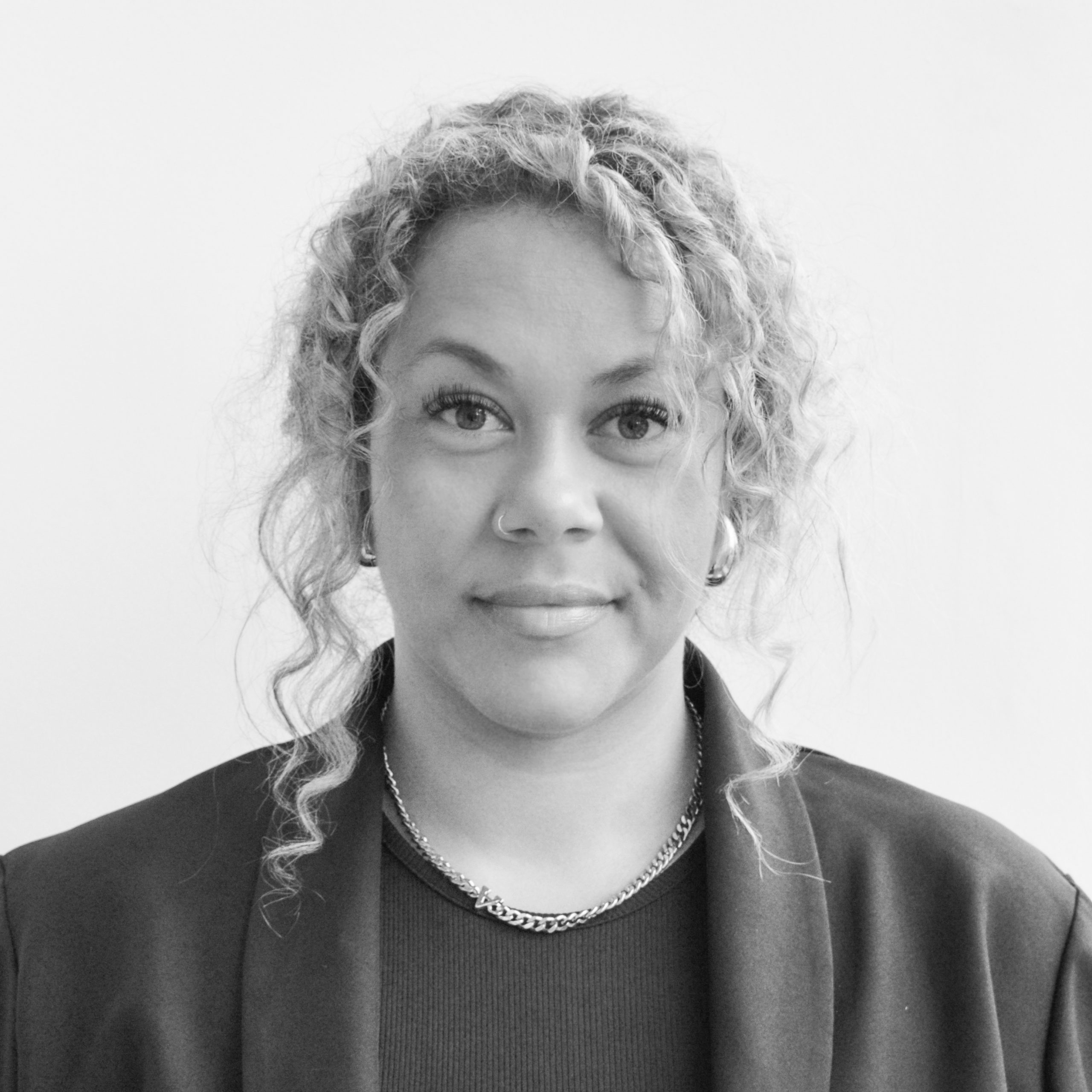 A black and white headshot image of a smiling woman against a white backdrop