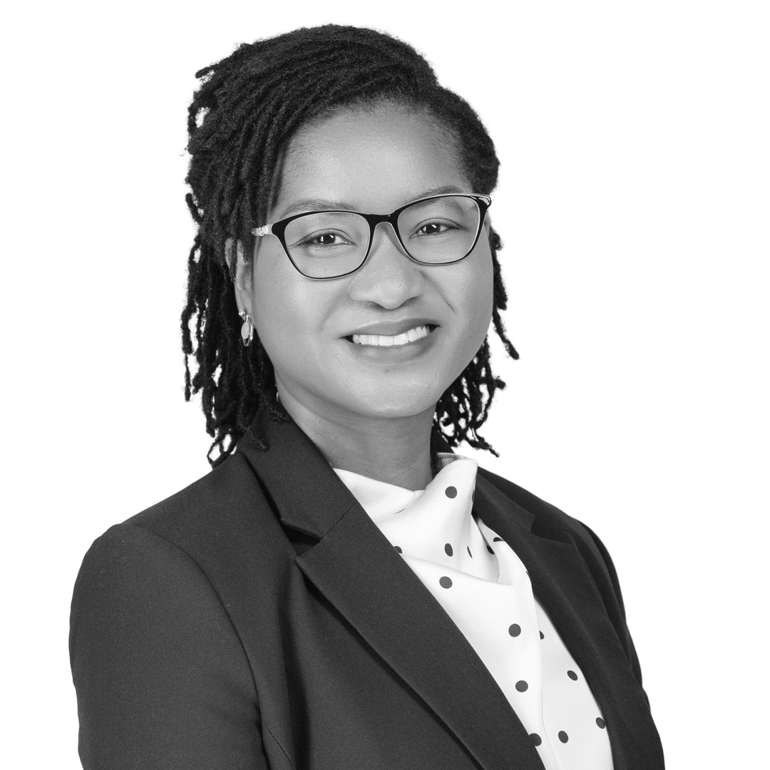 A black and white headshot image of a smiling woman against a white backdrop