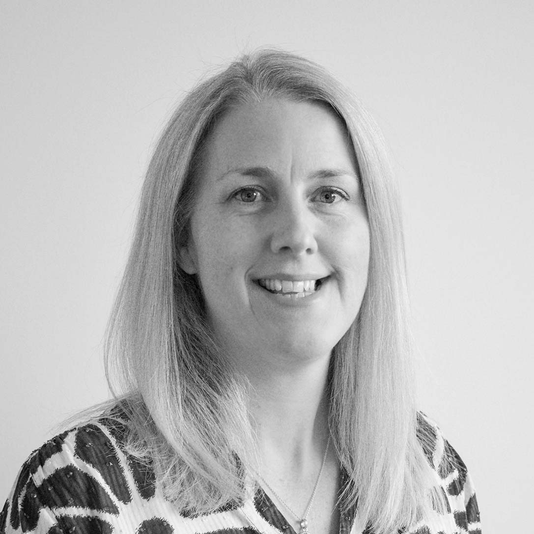 A black and white headshot image of a smiling woman against a white backdrop
