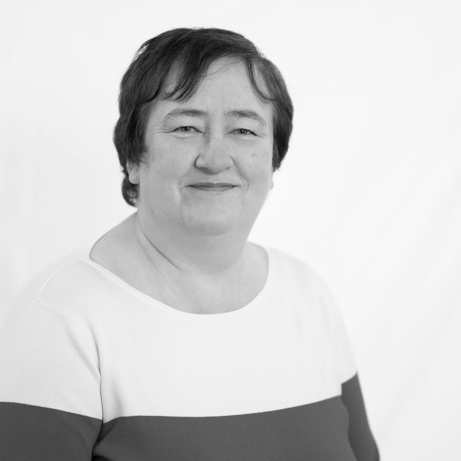 A black and white headshot image of a smiling woman against a white backdrop.