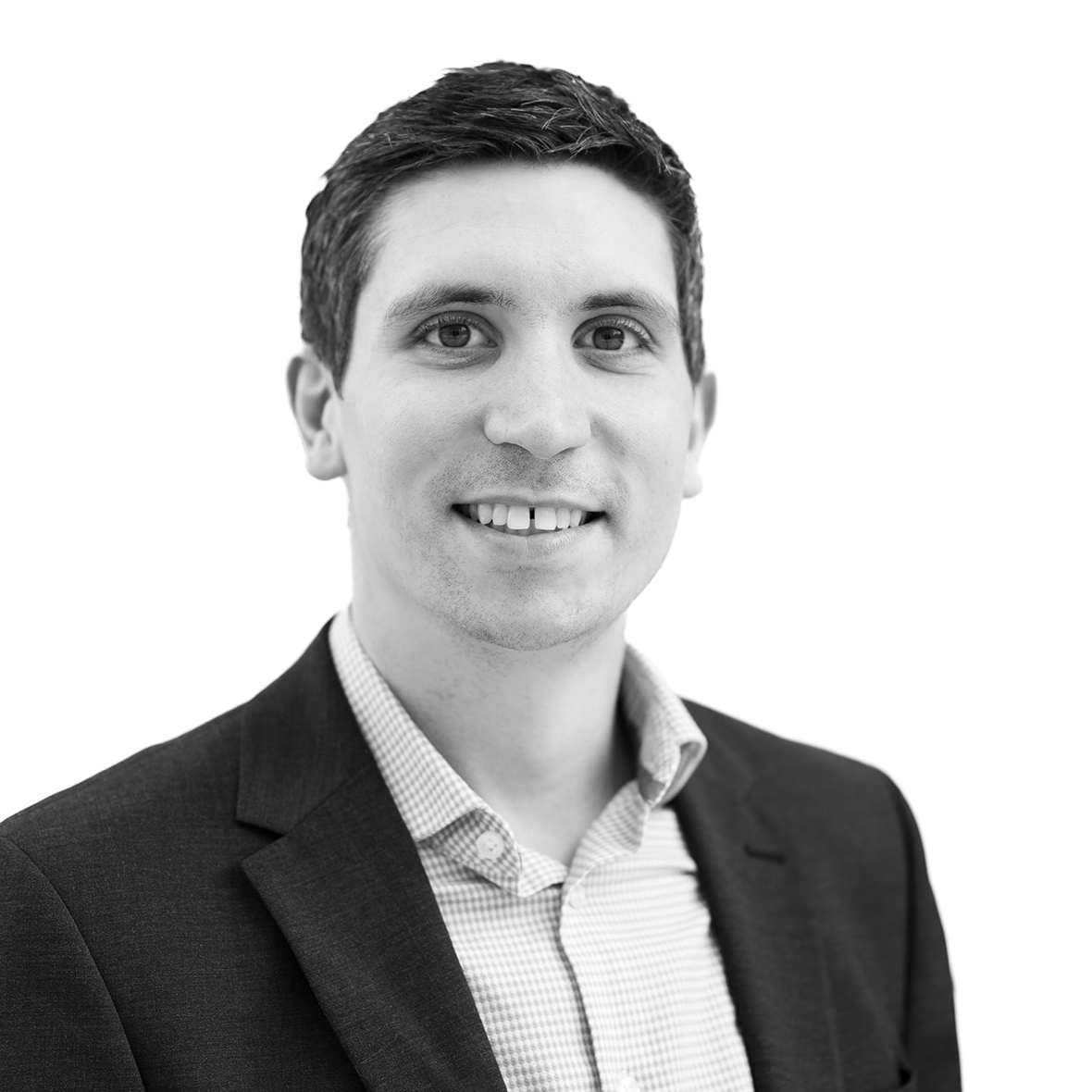 A black and white headshot image of a smiling man against a white backdrop