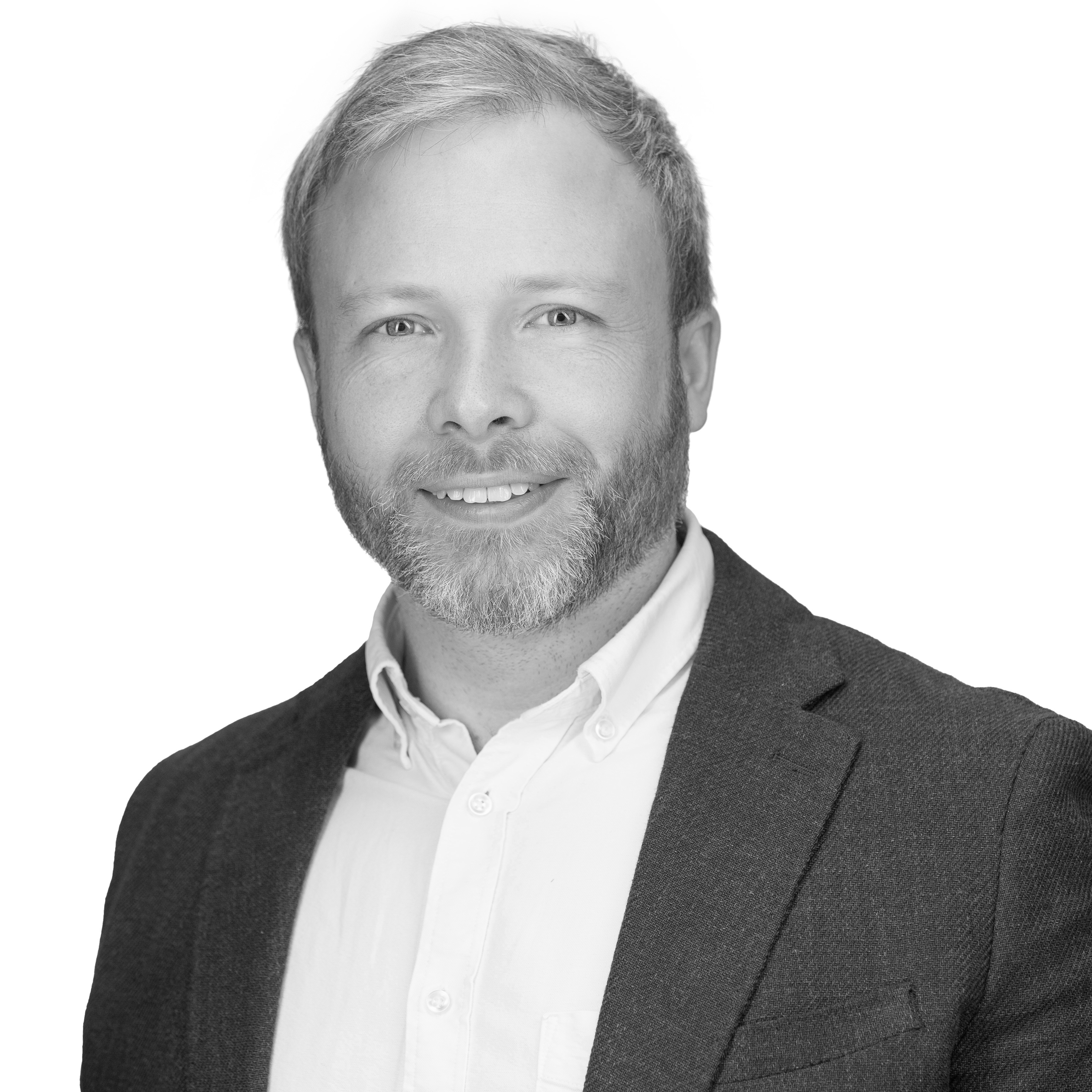 A black and white headshot image of a smiling man against a white backdrop