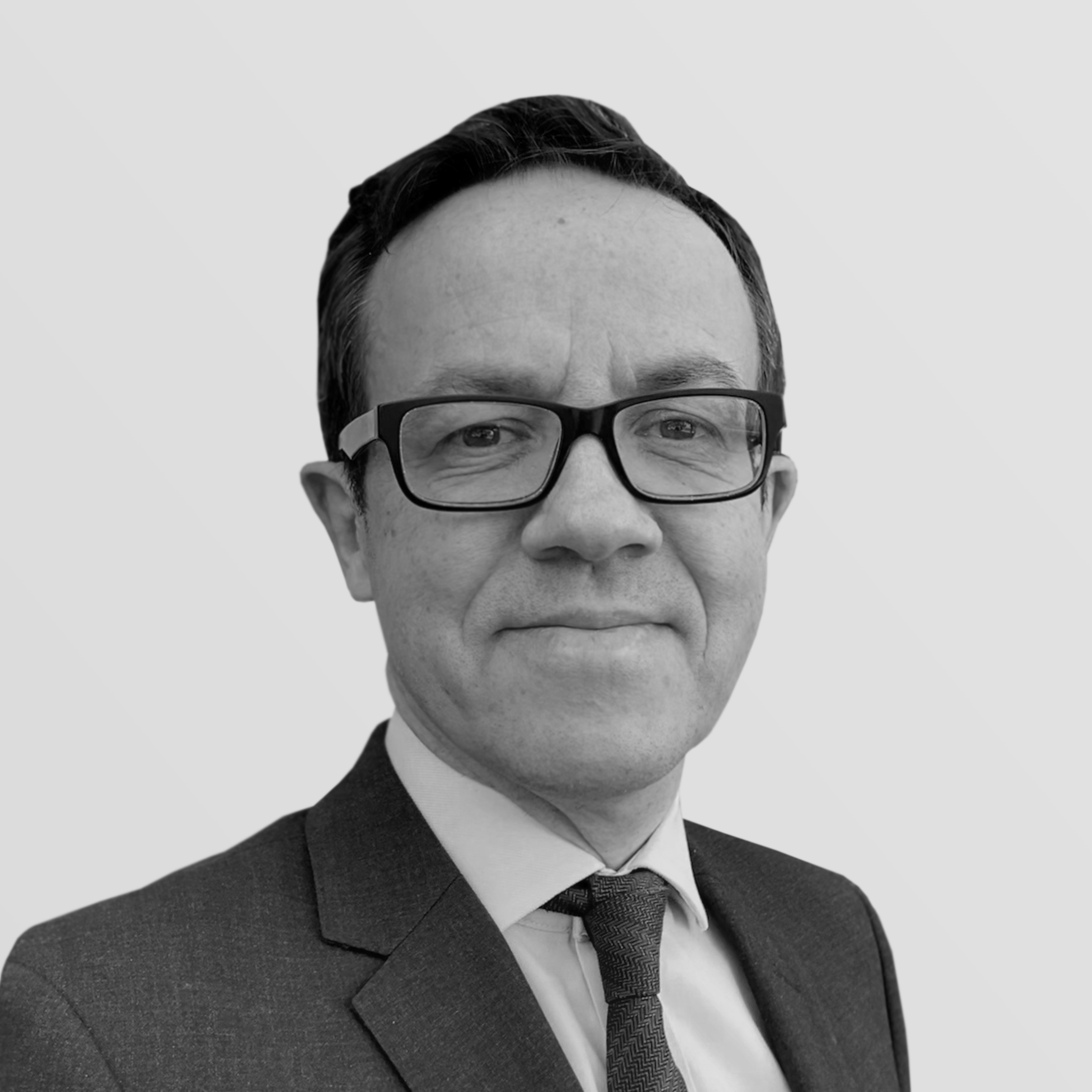 A black and white headshot image of a smiling man against a white backdrop