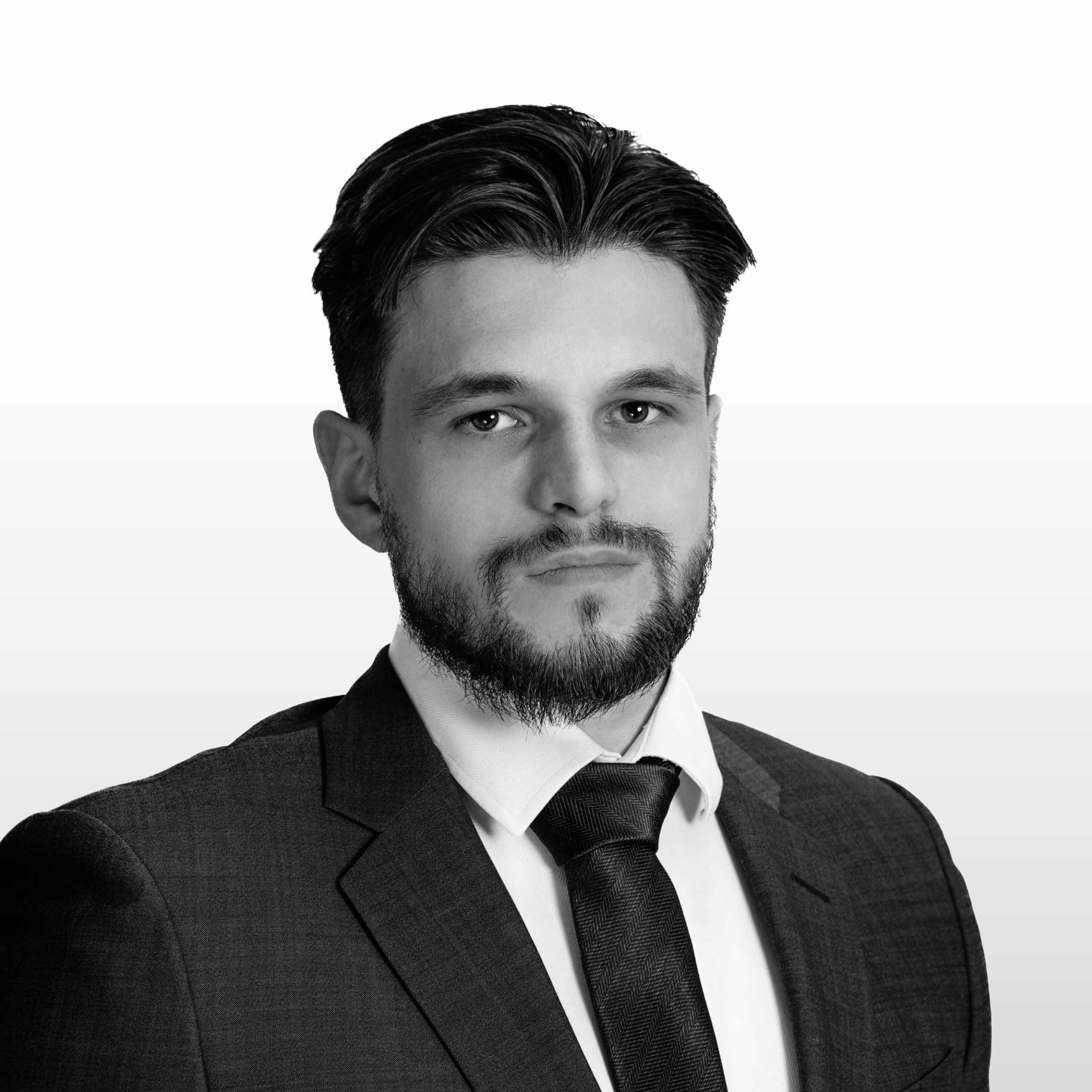 A black and white headshot image of a smiling man against a white backdrop