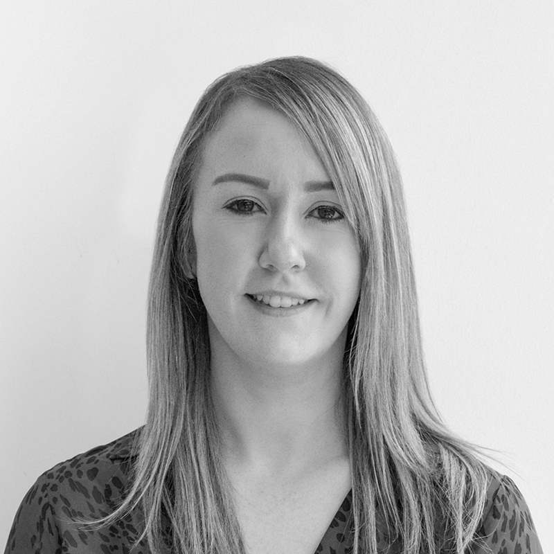 A black and white headshot image of a smiling woman against a white backdrop