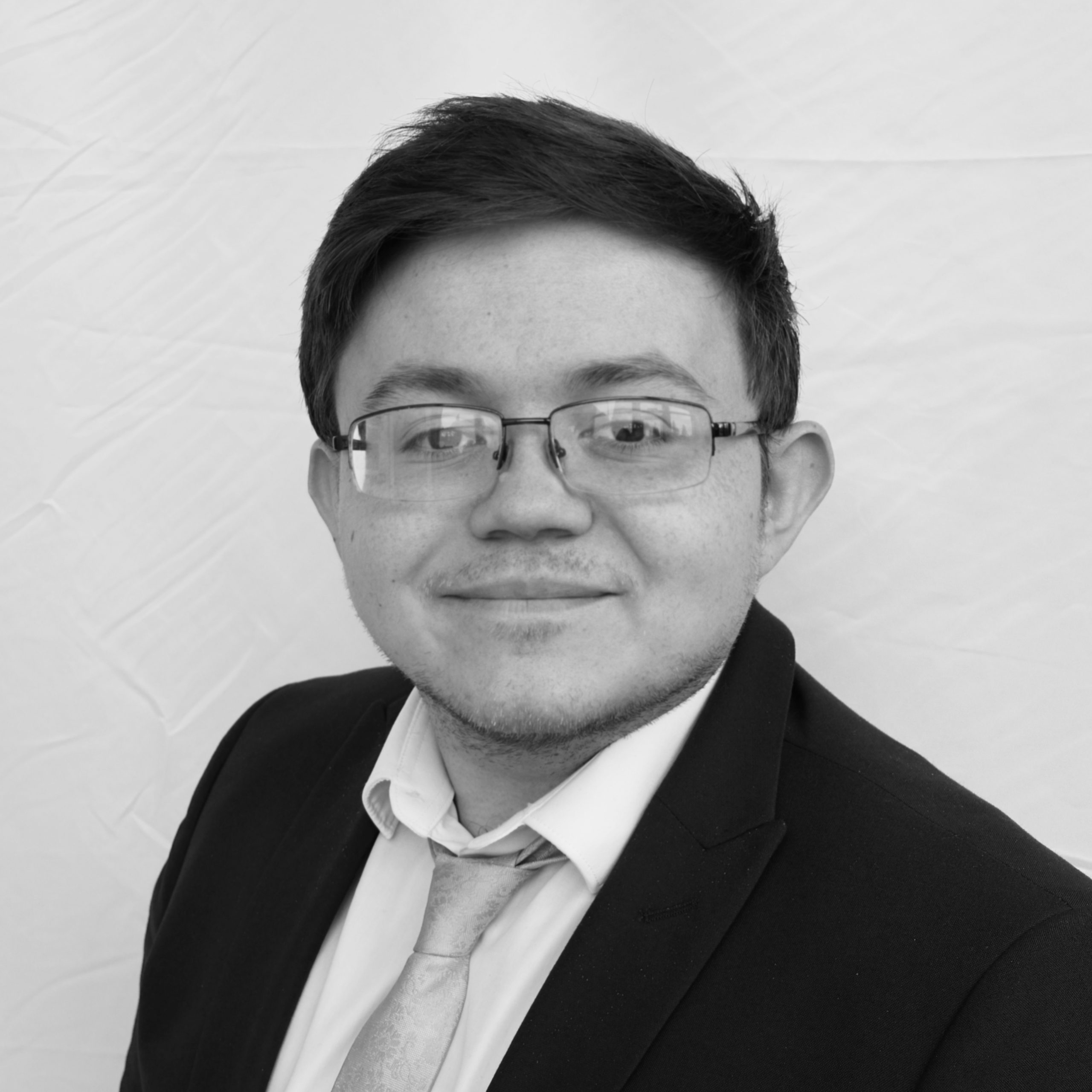 A black and white headshot image of a smiling man against a white backdrop