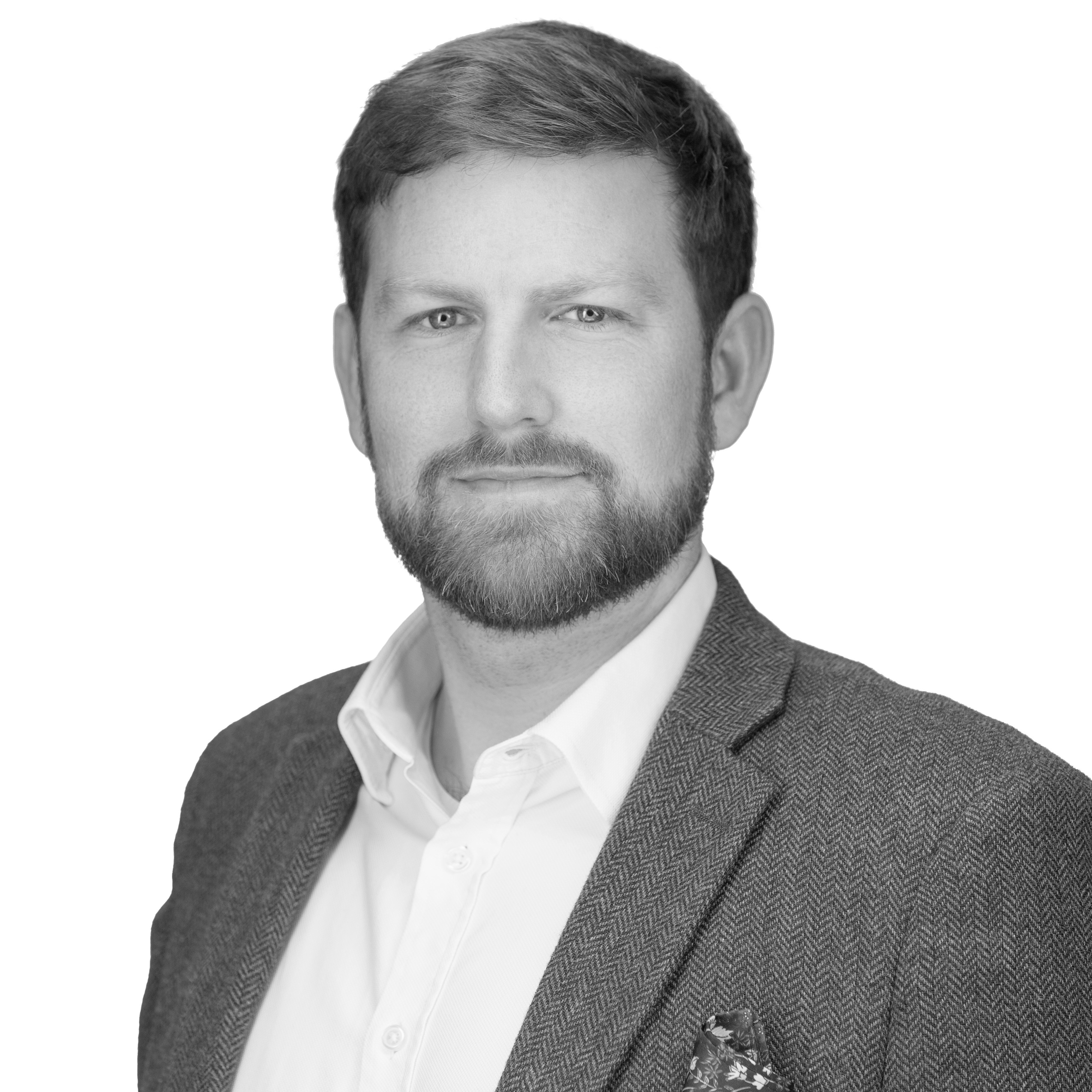 A black and white headshot image of a smiling man against a white backdrop
