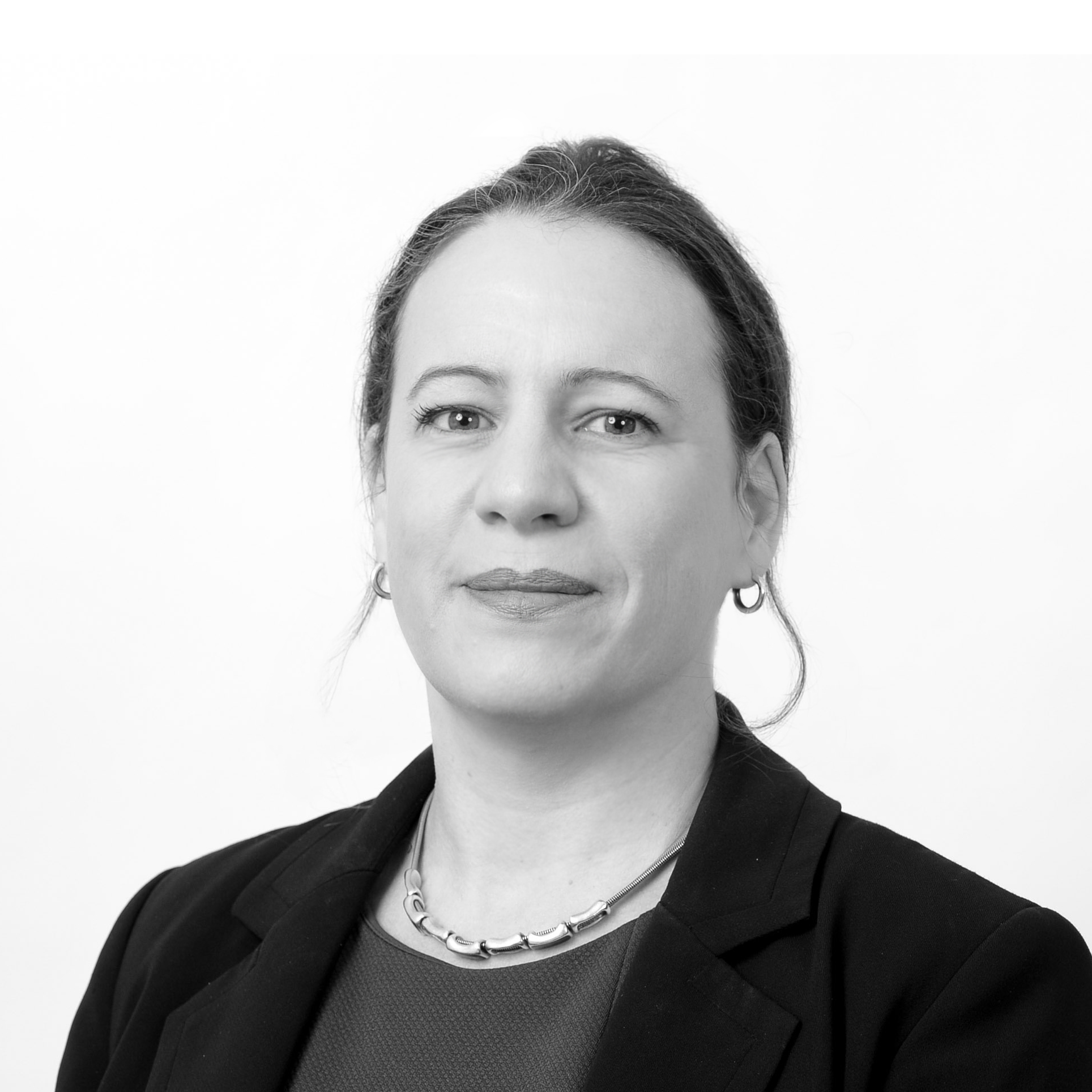 A black and white headshot image of a smiling woman against a white backdrop
