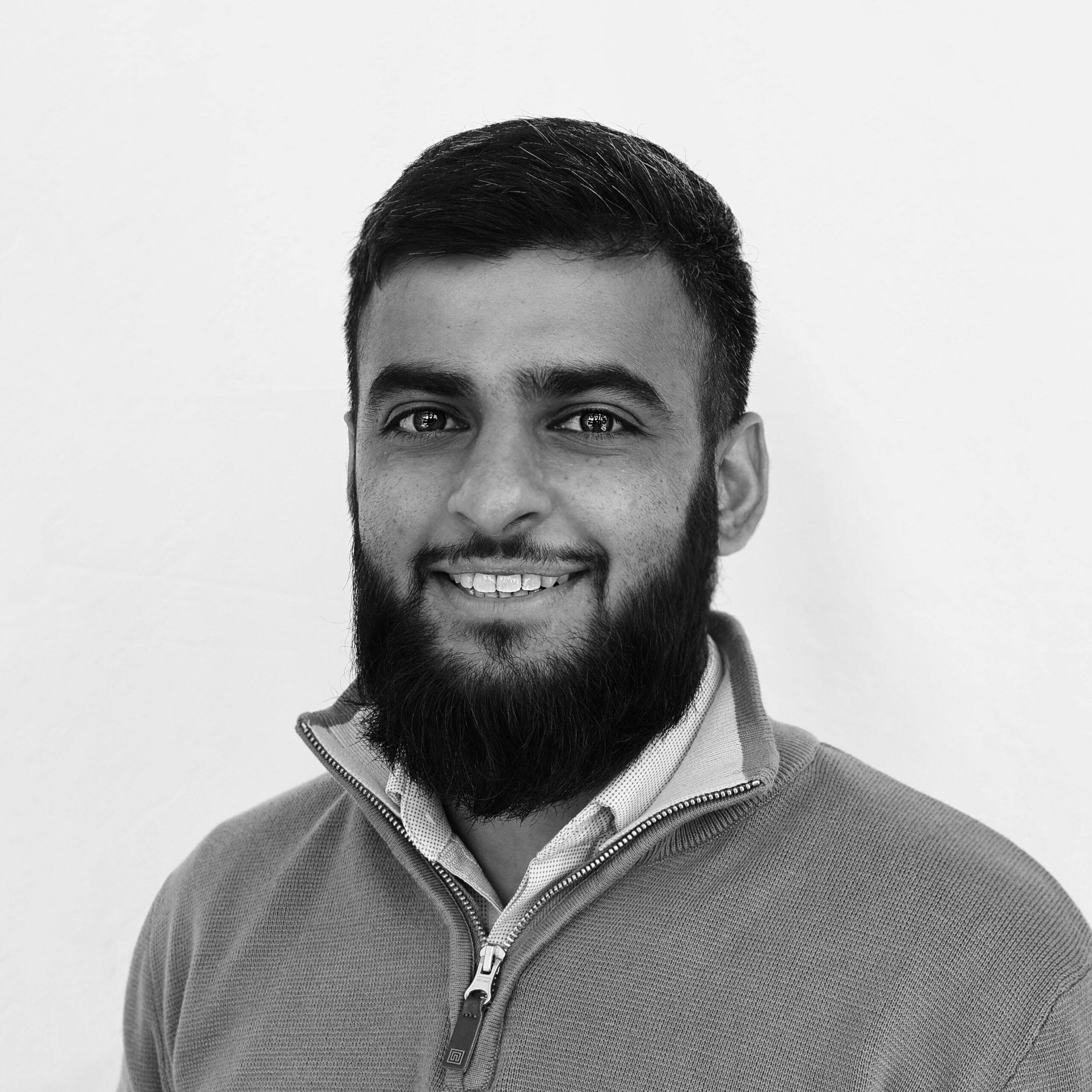 A black and white headshot image of a smiling man against a white backdrop
