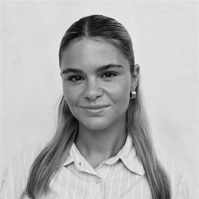 A black and white headshot image of a smiling woman against a white backdrop