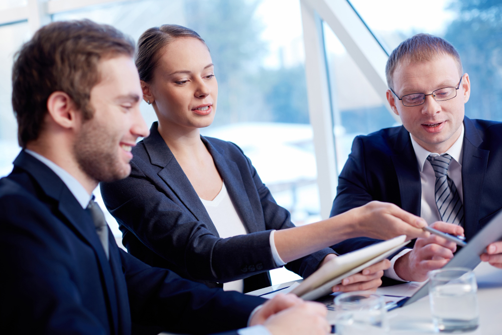 Three co-workers discussing information in front of them in an office setting.