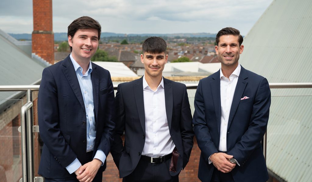 A professional photo of three colleagues looking happy and confident in front of an office park.