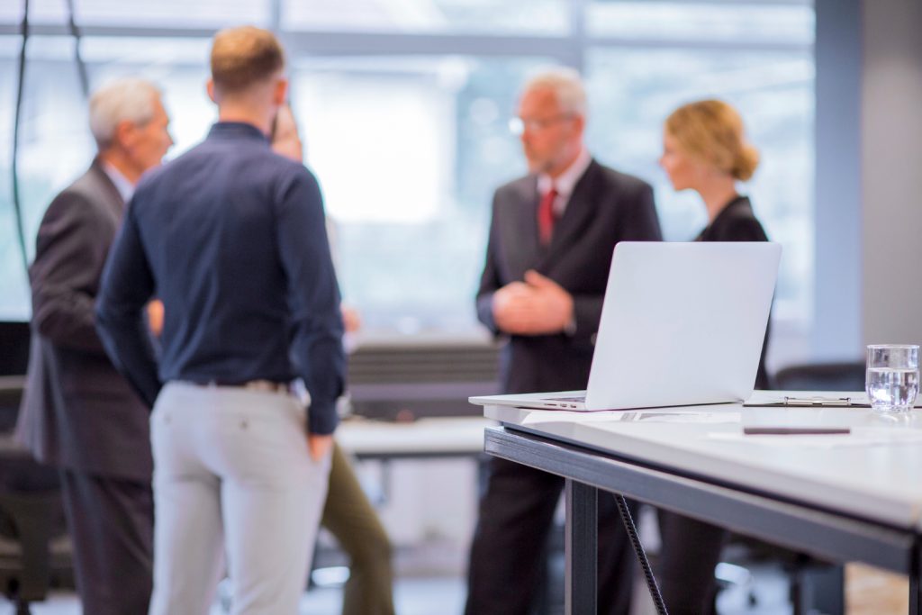Four professionals discussing work in front of a laptop