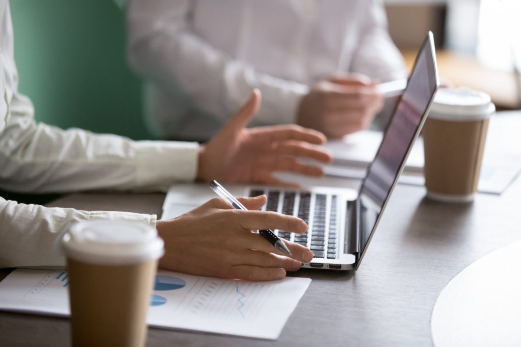 A man holding a pen while contemplating the information on his laptop screen