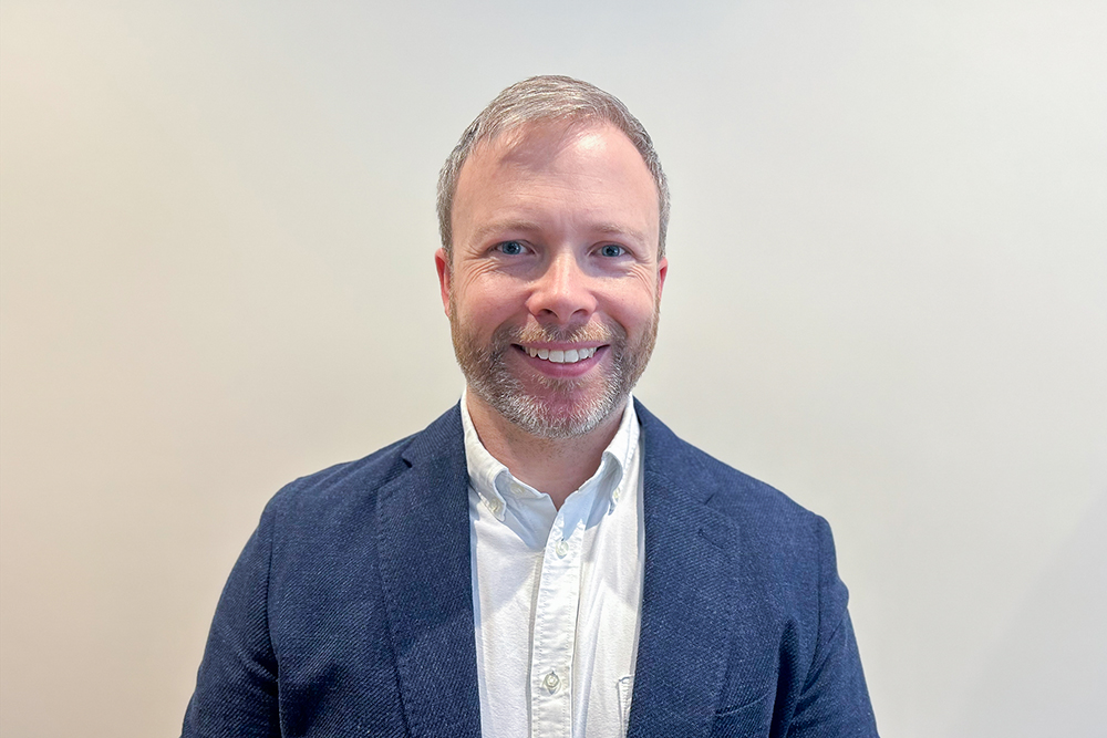 A headshot image of a smiling man against a white backdrop