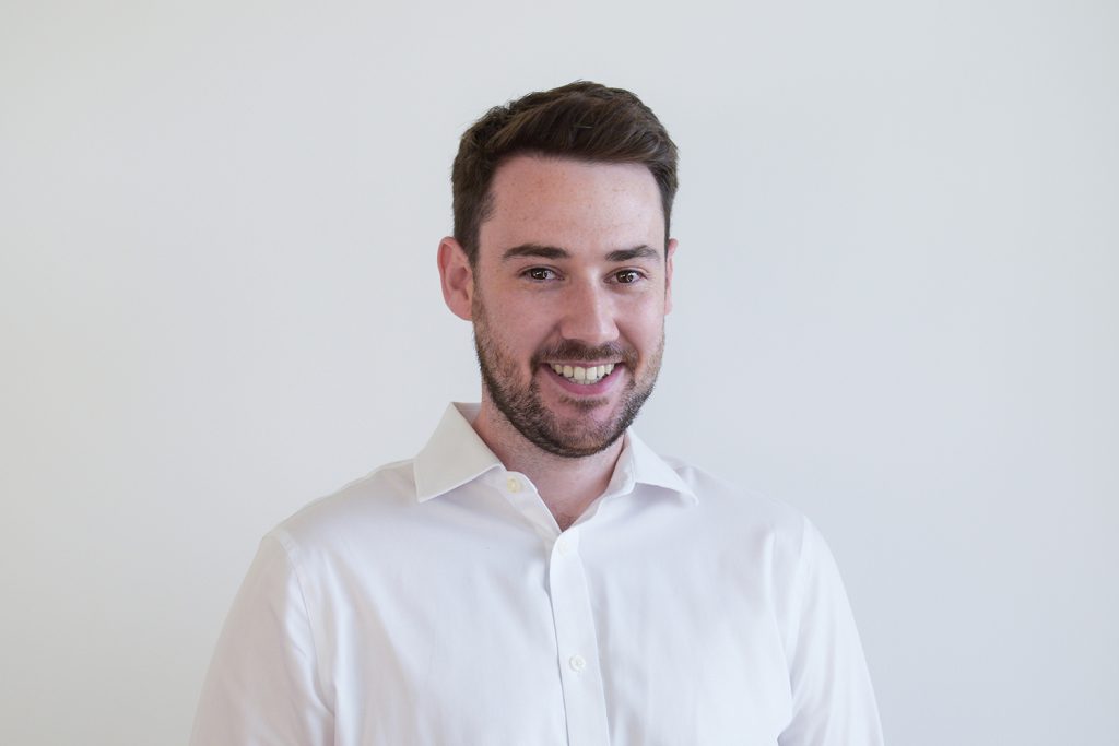A headshot image of a smiling man against a white backdrop.