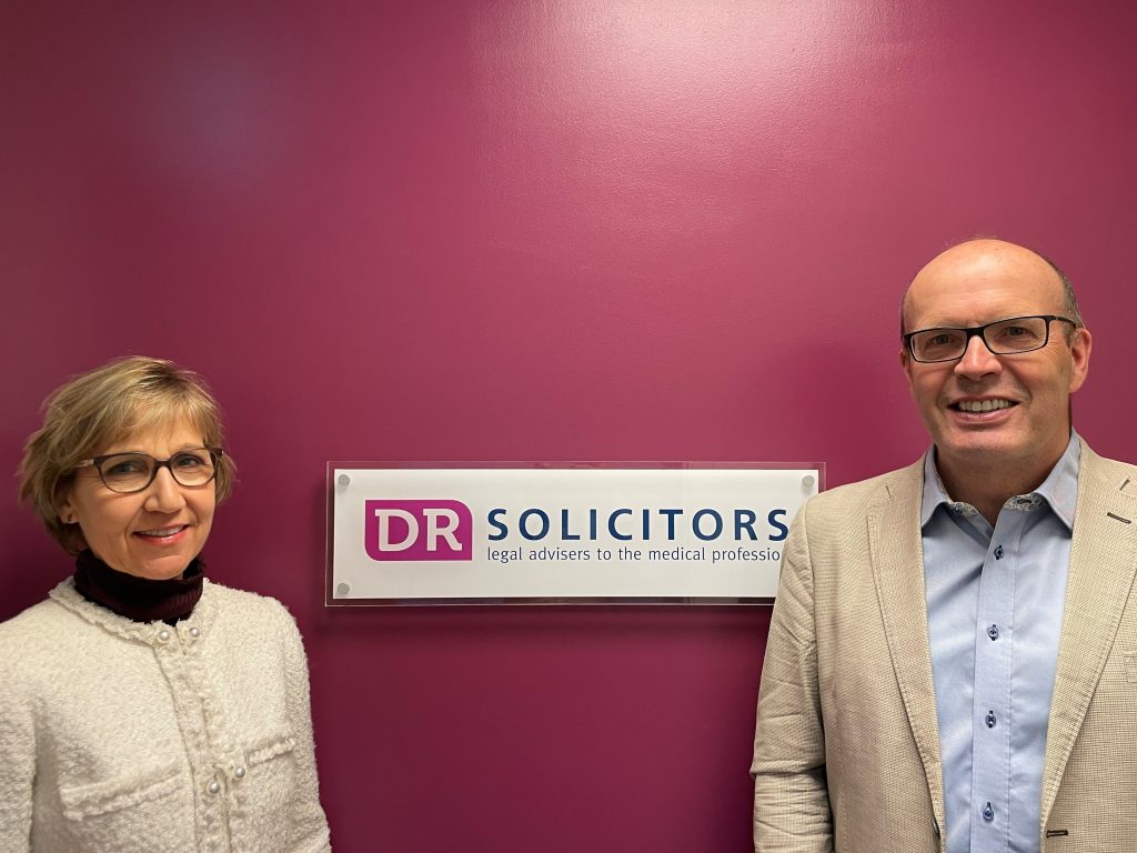 Company co-founders, Daphne Robertson, and Nils Christensen, standing together in front of the DR Solicitors logo.