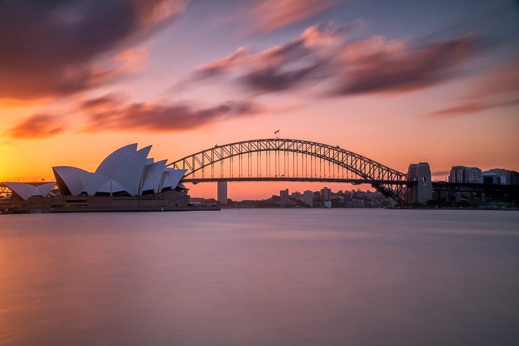 A shot of Sydney Harbour Bridge with a light pink-blue sky.