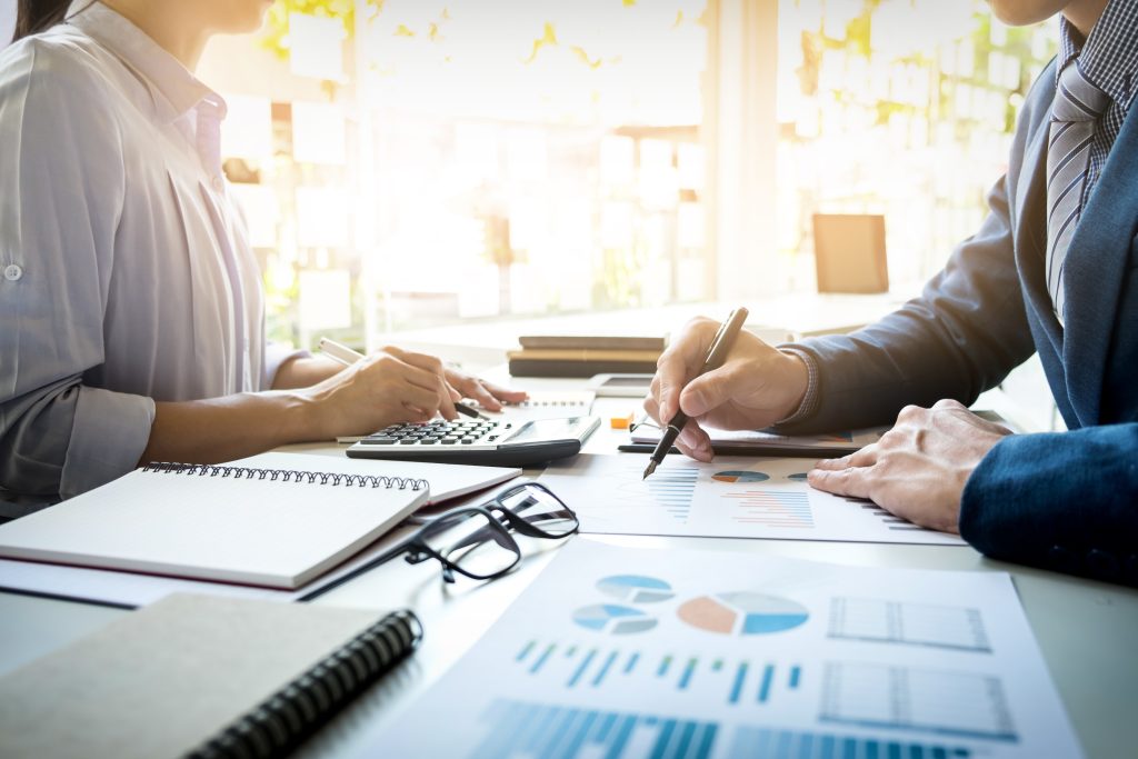 Two data analysts, a man and woman, reviewing a printed financial growth chart.