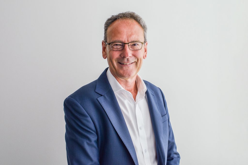 A headshot image of a smiling man against a white backdrop